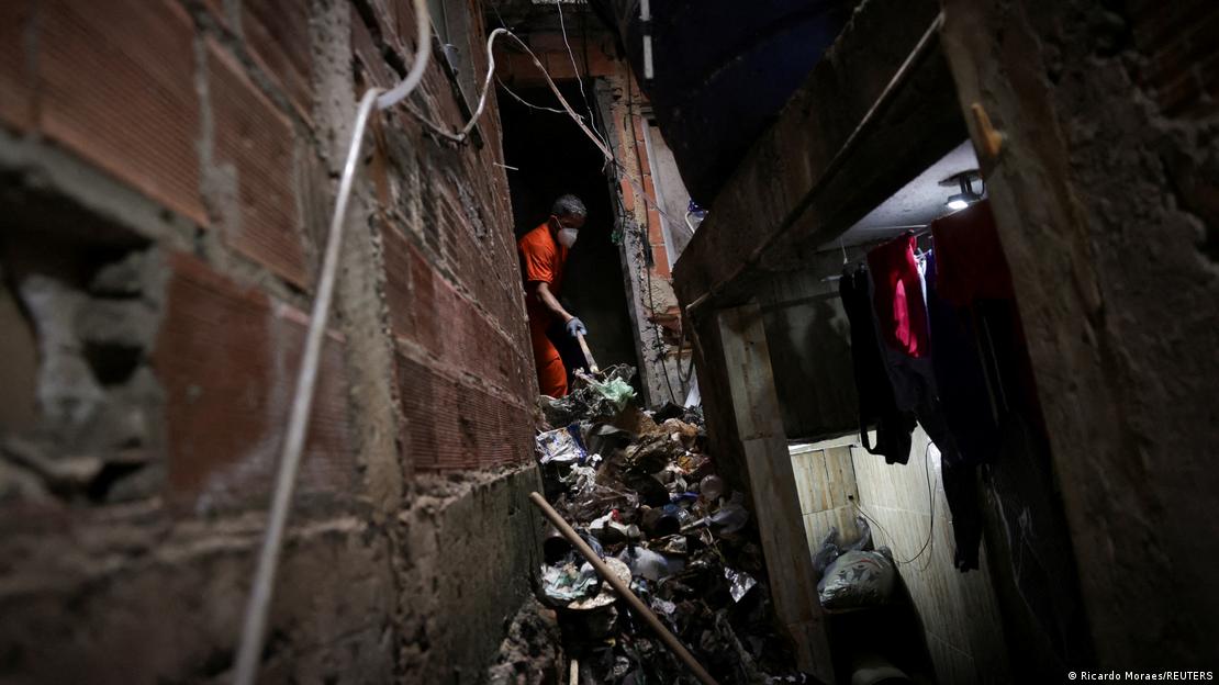 Homem de uniforme laranja e máscara realiza a limpeza de um imóvel abandonado