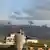 Smoke rises following Israeli airstrikes in Khiam, Lebanon, as two people look on