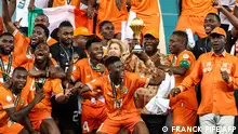 TOPSHOT - President of Ivory Coast Alassane Ouattara (C) lifts the Africa Cup of Nations trophy on the podium after Ivory Coast won the Africa Cup of Nations (CAN) 2024 final football match between Ivory Coast and Nigeria at Alassane Ouattara Olympic Stadium in Ebimpe, Abidjan on February 11, 2024. (Photo by FRANCK FIFE / AFP)