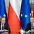 Zwei Männer (Donald Tusk und Andrzej Duda) an einem Tisch vor Europa- und polnischen Fahnen