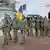 A line of Ukrainian servicemen carry the coffin of Diana Savita Wagner and an image of her in combat fatigues