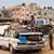 Gazze Şeridi'nin güneyindeki Refah'ta, bagajı ve üstü eşyalarla yüklenmiş beyaz bir otomobil, üstünde ve yanıbaşında birer çocuk, arka planda çadırlar, binalar - (13.02.2024 / Refah)