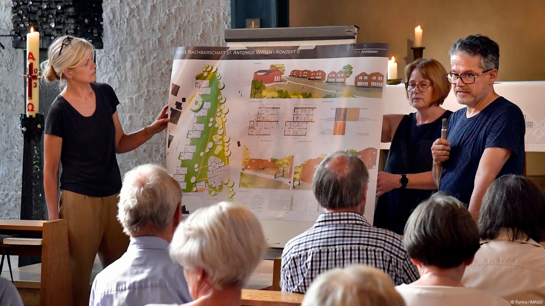 information event for parishioners who are sitting in the church looking at a drawing of the planned houses