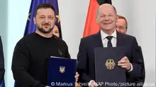 German Chancellor Olaf Scholz, right, and Ukrainian President Volodymyr Zelenskyy display the treaties they signed in the chancellory in Berlin, Germany, Friday, Feb.16, 2024.(AP Photo/Markus Schreiber)