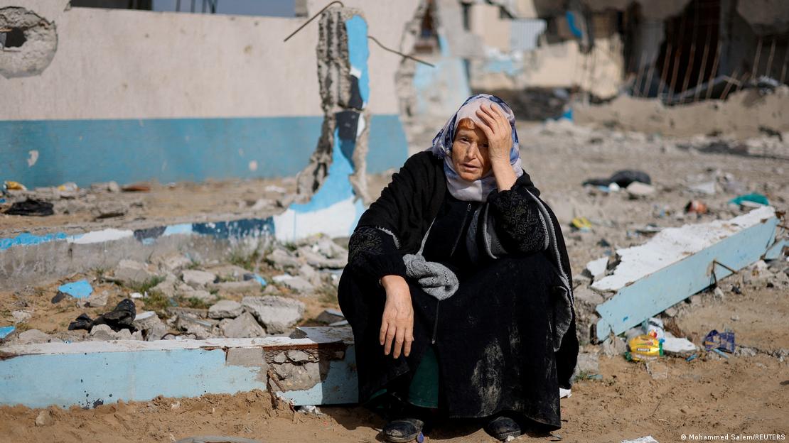 Një grua ulur në trotuarin e shkatërruar në Rafah