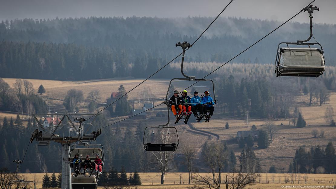 Skifahrer in einem Sessellift Mitte Februar im Adlergebirge in Tschechien ohne Schnee