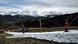 Skiers ride a ski tow on a slope lacking snow Skiers ride a ski tow on a slope lacking snow