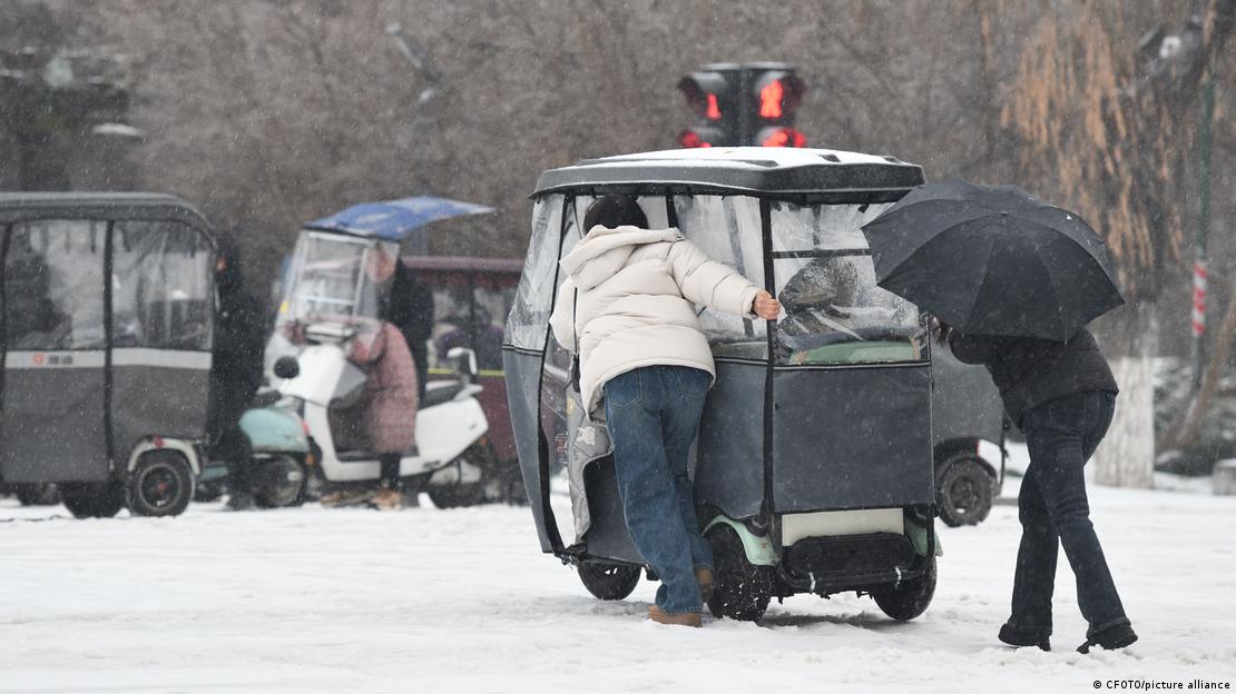 People pushing a tricycle in the snow