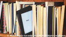 Hölzernes Bücherregal mit E-Book-Reader inmitten klassischer Bücher