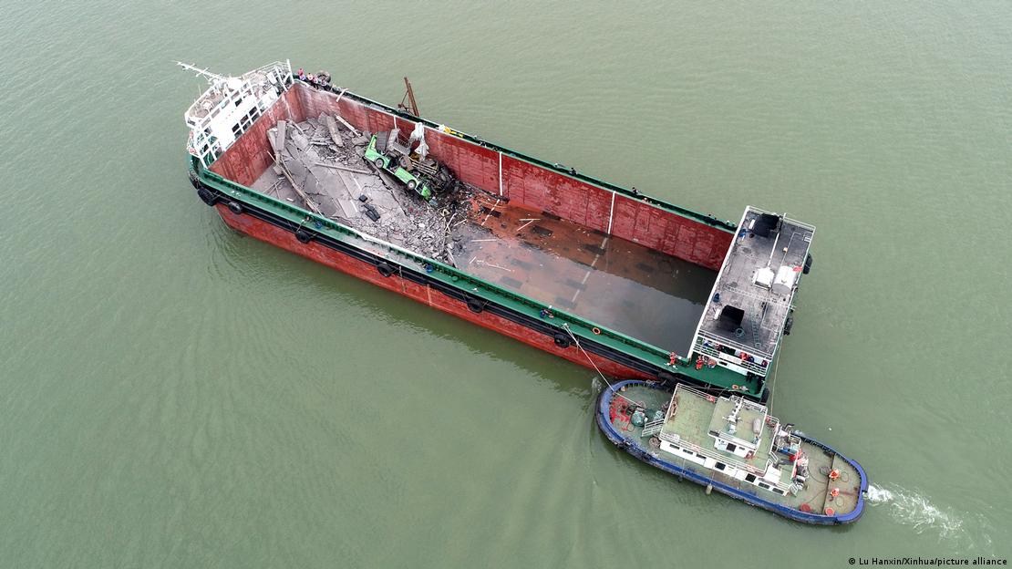 The container ship which hit the Lixinsha Bridge being towed away. Debris of vehicles which have fallen from the bridge are seen in the ship. 