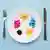 Colorful pills in a large white plate along with a fork and knife 