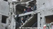 22/02/2024**TOPSHOT - Palestinian women and children look on as they stand at the structure of a heavily damaged building on February 22, 2024, following overnight Israeli air strikes in Rafah refugee camp in the southern Gaza Strip, as battles between Israel and the Palestinian militant group Hamas continue. (Photo by MOHAMMED ABED / AFP) (Photo by MOHAMMED ABED/AFP via Getty Images)