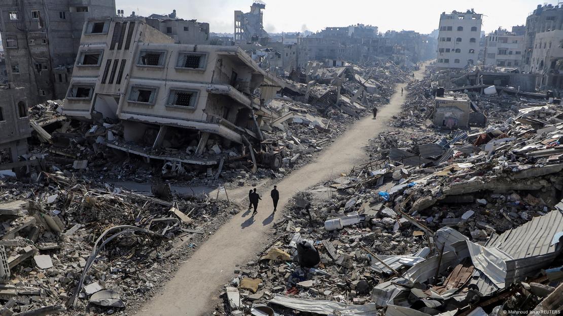 Palestinians walk past destroyed houses, amid the ongoing conflict between Israel and Hamas