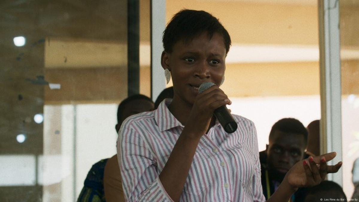 Film still from 'Dahomey': An African woman talking in a microphone.