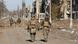 Russian troops walk along a debris-filled road in Avdiivka Russian troops walk along a debris-filled road in Avdiivka