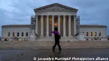 A woman under a purple umbrella walks past the Supreme Court, Wednesday, Feb. 28, 2024, in Washington. The Supreme Court agreed on Wednesday to decide whether former President Donald Trump can be prosecuted on charges he interfered with the 2020 election and has set a course for a quick resolution. (AP Photo/Jacquelyn Martin)