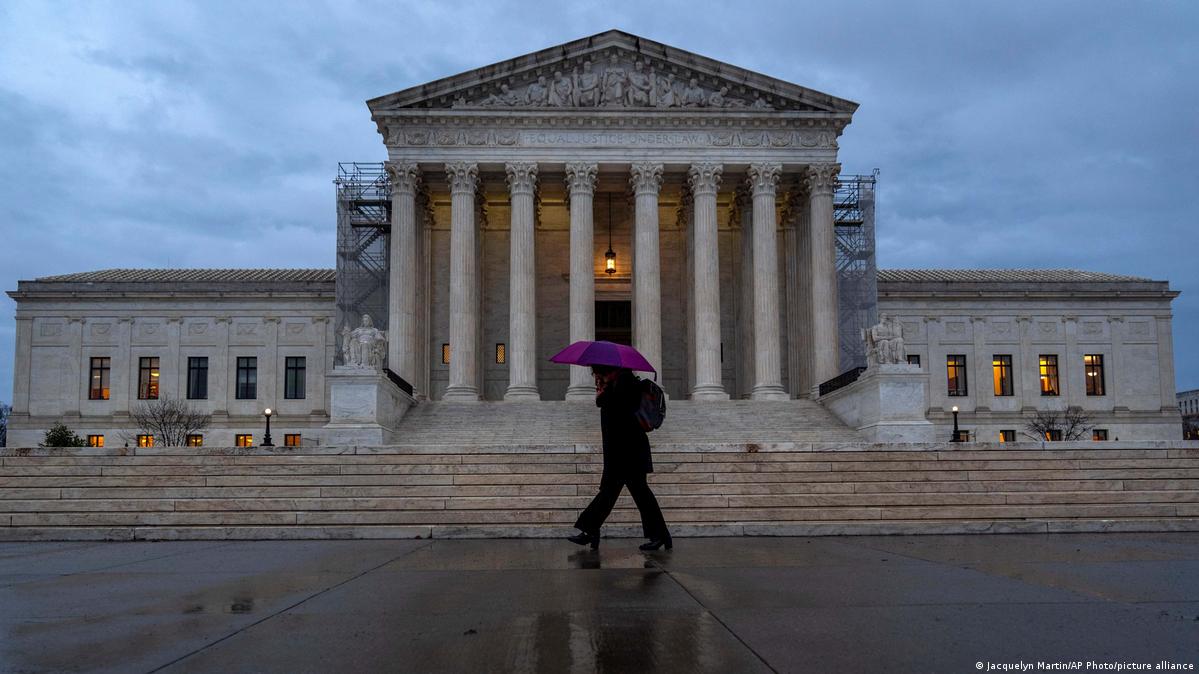 File picture of a woman under a purple umbrella walking past the Supreme Court