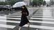 A woman holding an umbrella crosses a road in central Seoul A woman holding an umbrella crosses a road in central Seoul