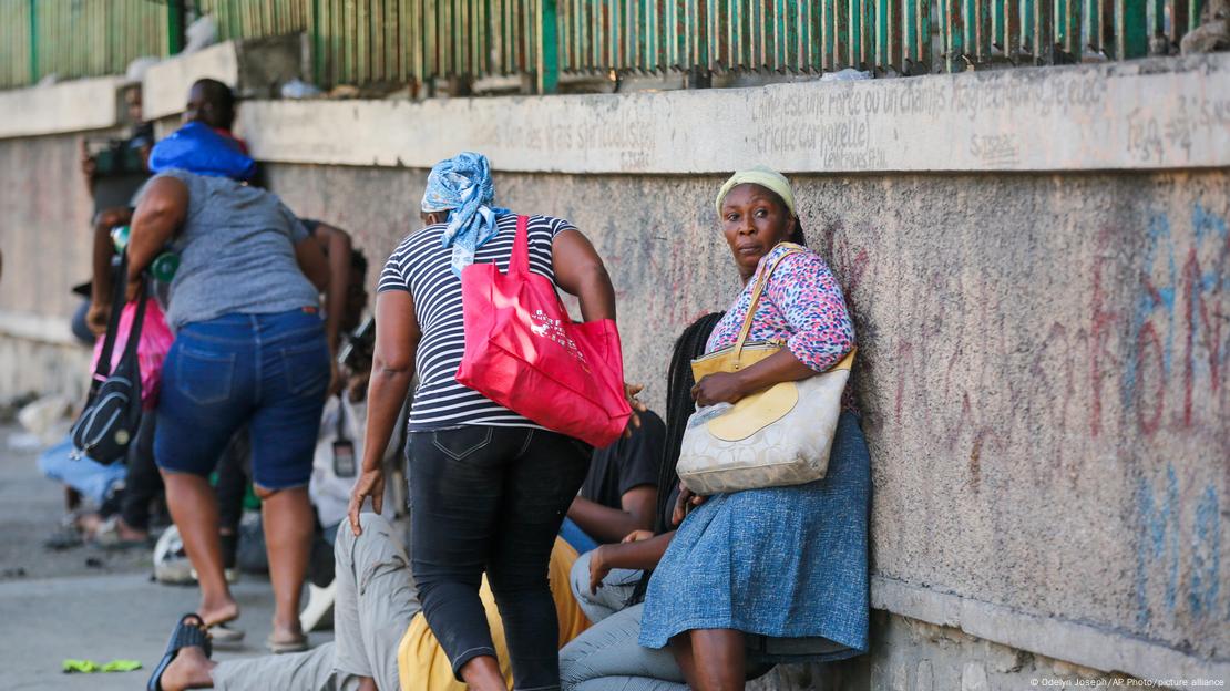 Mujeres corren para resguardarse durante enfrentamientos armados entre policías y pandilleros en Puerto Príncipe el viernes (01.03.2024).