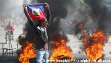A demonstrator holds up an Haitian flag during protests demanding the resignation of Prime Minister Ariel Henry in Port-au-Prince, Haiti, Friday, March 1, 2024. (AP Photo/Odelyn Joseph)