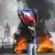 Homem grita erguendo bandeira do Haiti, fogueira ao fundo