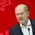 Olaf Scholz against a bright red backdrop