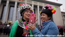 Ethnic minority delegates share a light moment outside the Great Hall of the People after attending the opening session of the National People's Congress (NPC) in Beijing, Tuesday, March 5, 2024. China's official growth target for this year is around 5%, Premier Li Qiang said Tuesday in an annual report on the government's plans and performance that prioritized both security and the economy. (AP Photo/Andy Wong)