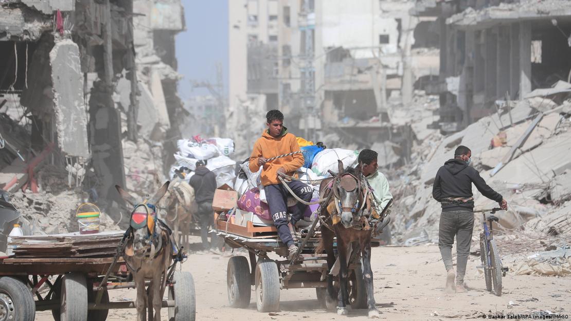 Jóvenes en un carro conun caballo atravesando las ruinas y escombros en una calle de Jan Yunis, Gaza.