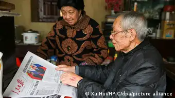 An elderly Chinese couple reading the newspaper together