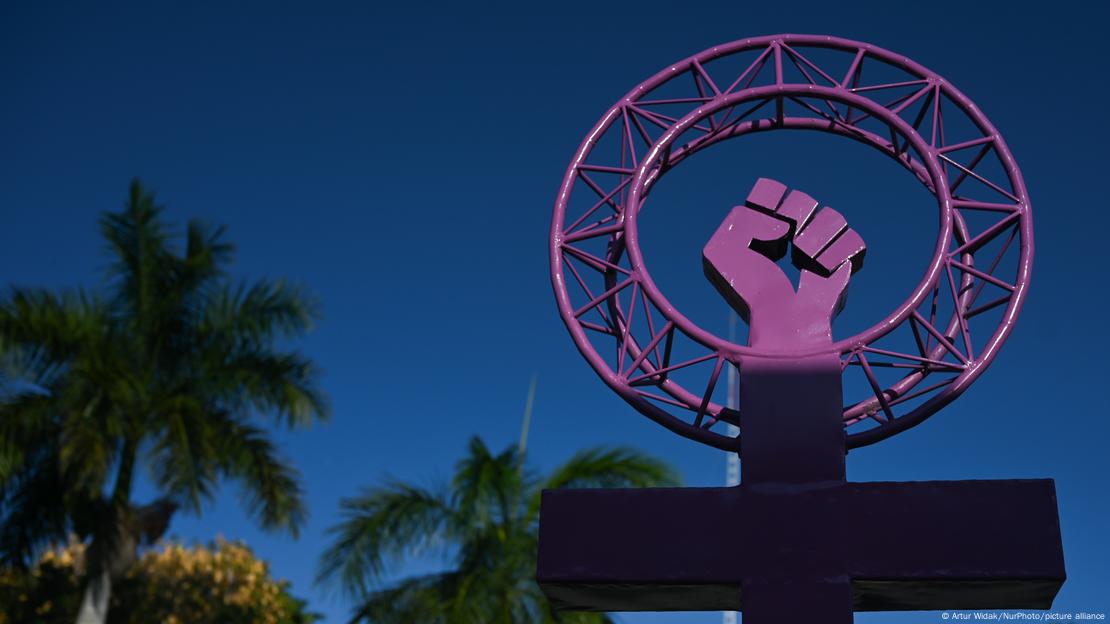 Escultura con una mano cerrada de color violeta.