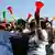 People wear T-shirts showing presidential candidate Khalifa Sall as they hang out of a car and blow vuvuzelas in the colors of the Senegalese flag