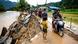 People walking past a road that was destroyed by flooding People walking past a road that was destroyed by flooding