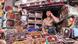 A vendor is sitting in his stall at the market, nuts and dates in front of him