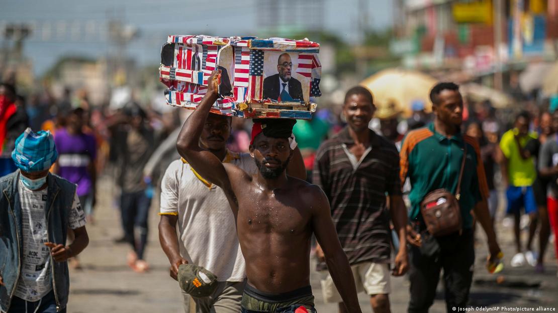 Manifestante carrega caixão com foto do premiê haitiano Ariel Henry e bandeira dos EUA