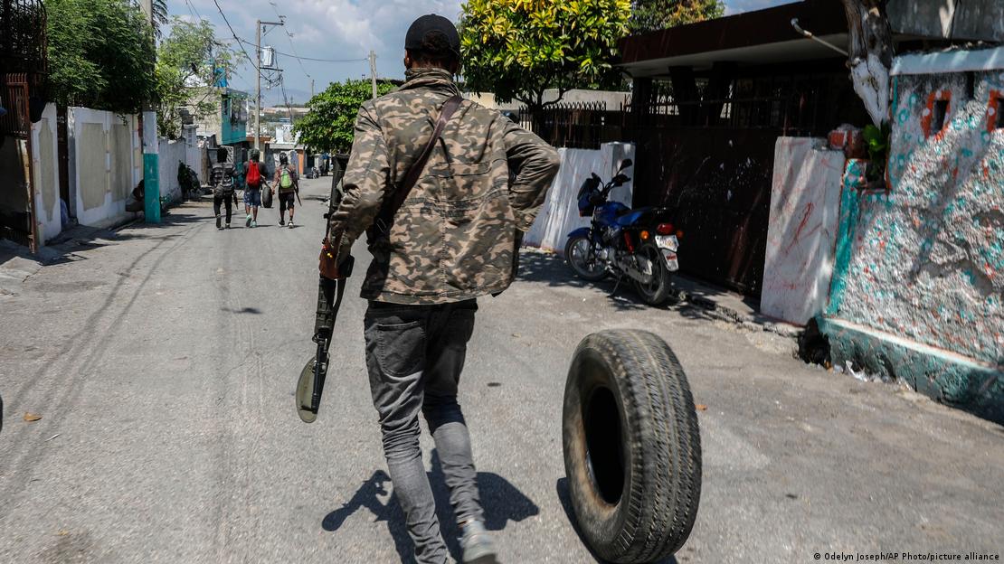 Un miembro armado de la pandilla G9 y Familia rueda una llanta para quemarla en un control de carretera en el vecindario Delmas 6 de Puerto Príncipe.
