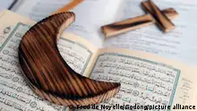 A wooden cross lies on a Bible while a wooden crescent lies on a Quran