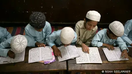 Young Koran students in Hyderabad, India, sit bent over the Koran and study. 