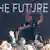 Elon Musk greets workers in front of a sign the reads ' the future' 