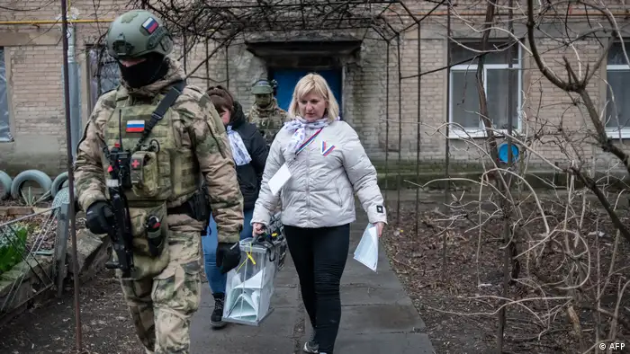 顿涅茨克俄占区，工作人员在军人护送下上门让居民投票