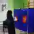 Избирательница на выборах президента РФ перед кабинкой для голосования