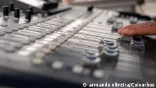 A hand pushes some sliders on a sound mixer