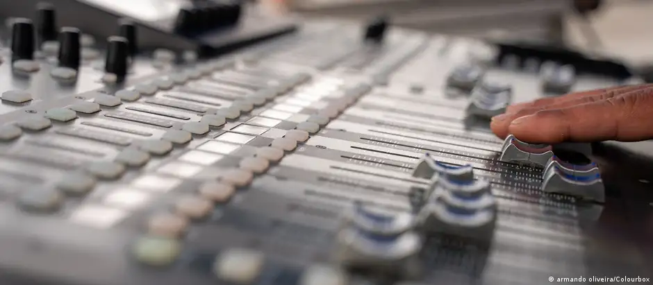A hand pushes some sliders on a sound mixer