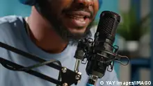 Close up of african american vlogger using microphone Close up of african american vlogger using microphone for conversation with subscribers on social media podcast. Black influencer working with modern equipment for online broadcasting Copyright: xx 43130488