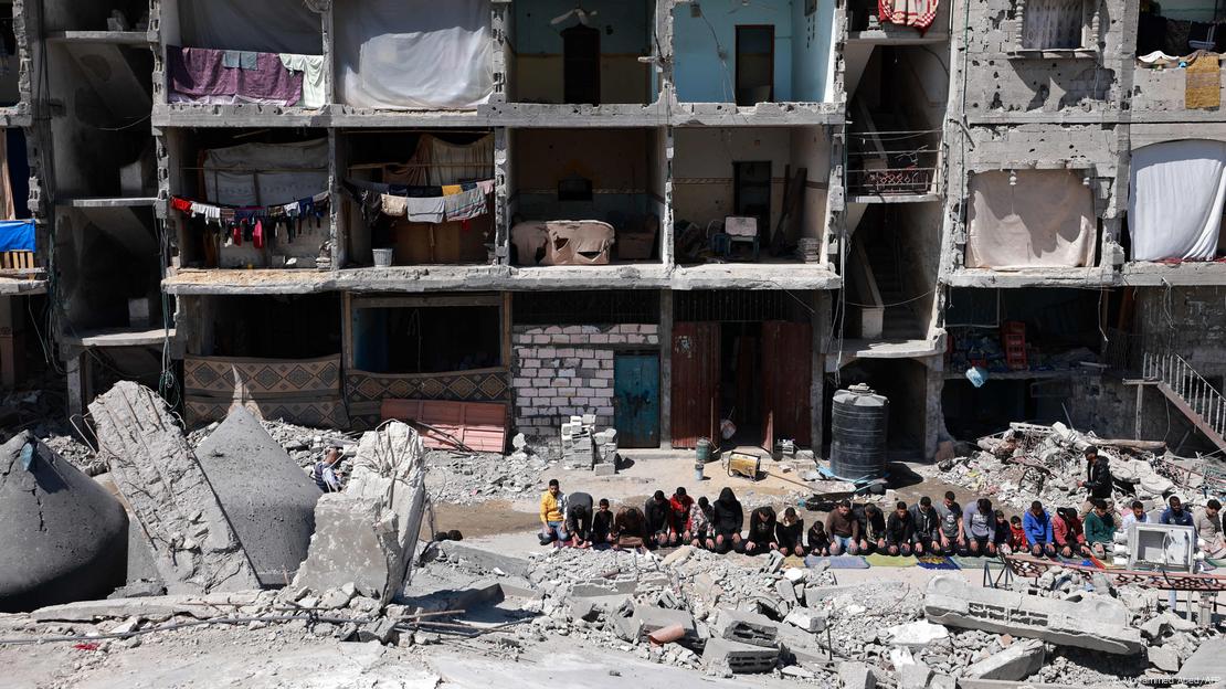 Pessoas rezam durante mês do Ramadã em frente a edificio destruído usado como abrigo em Rafah