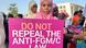 A woman holds up a placard that says, "Do not repeal the anti-FGM/C law" A woman holds up a placard that says, "Do not repeal the anti-FGM/C law"