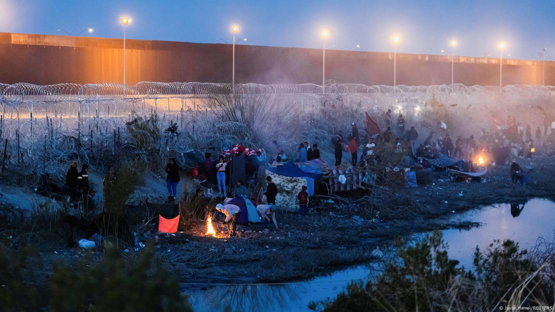 Eine Gruppe von Migranten kampiert auf der US-Seite des Rio Grande entlang der Grenzmauer zu Mexiko