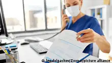 medicine, people and healthcare concept - female doctor or nurse wearing face protective medical mask for protection from virus disease with computer and clipboard calling on phone at hospital