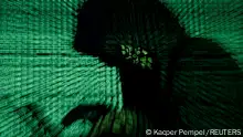 FILE PHOTO: A man holds a laptop computer as cyber code is projected on him in this illustration picture taken on May 13, 2017. REUTERS/Kacper Pempel/Illustration/File Photo