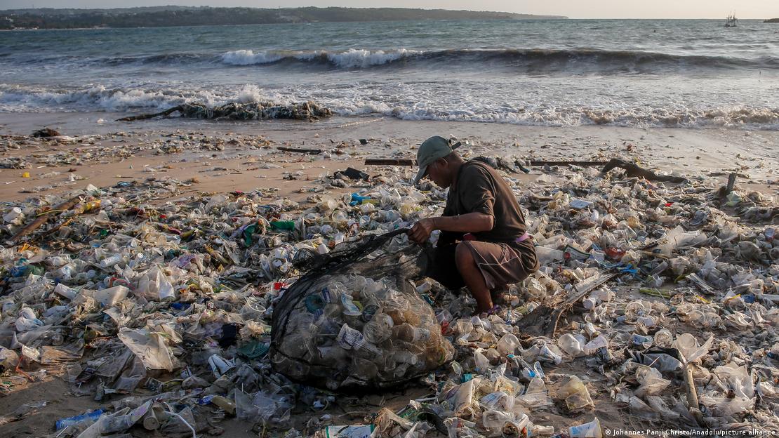Një person duke mlbedhur mbetjet plastike në breg të detit