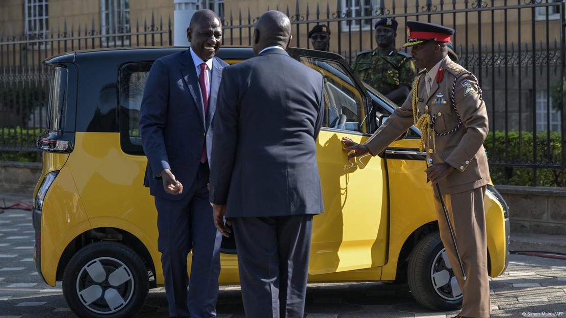 William Ruto getting out of a small yellow car, with military staff around